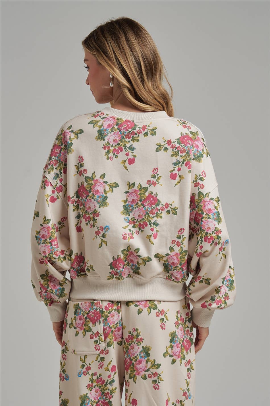 A woman model wearing a floral pajama set facing a gray background