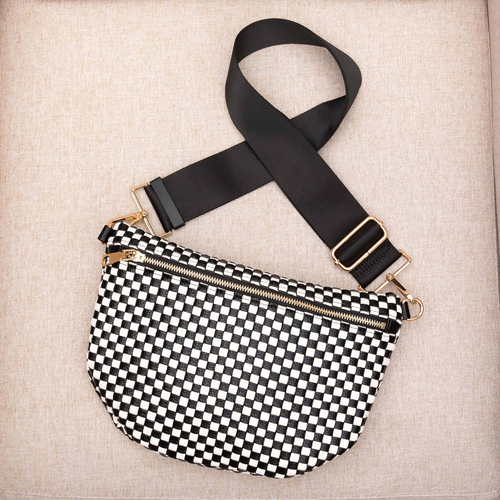 Black and white checkered bag with a black strap on a beige background