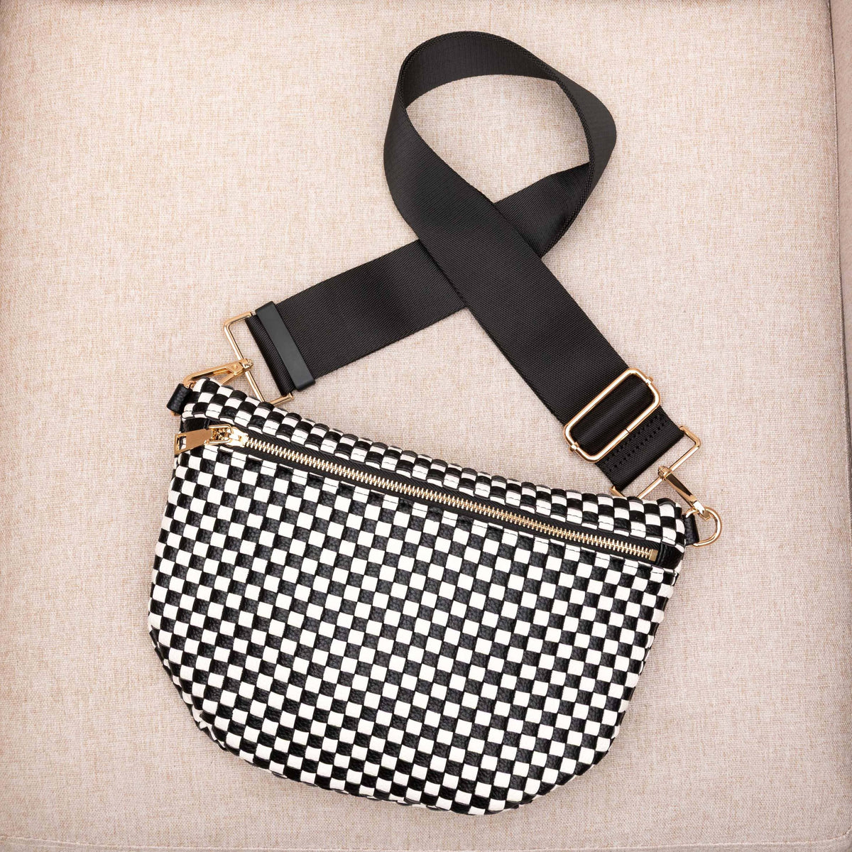 Black and white checkered bag with a black strap on a beige background