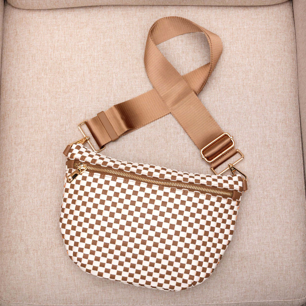Brown and white checkered bag with a brown strap on a beige surface