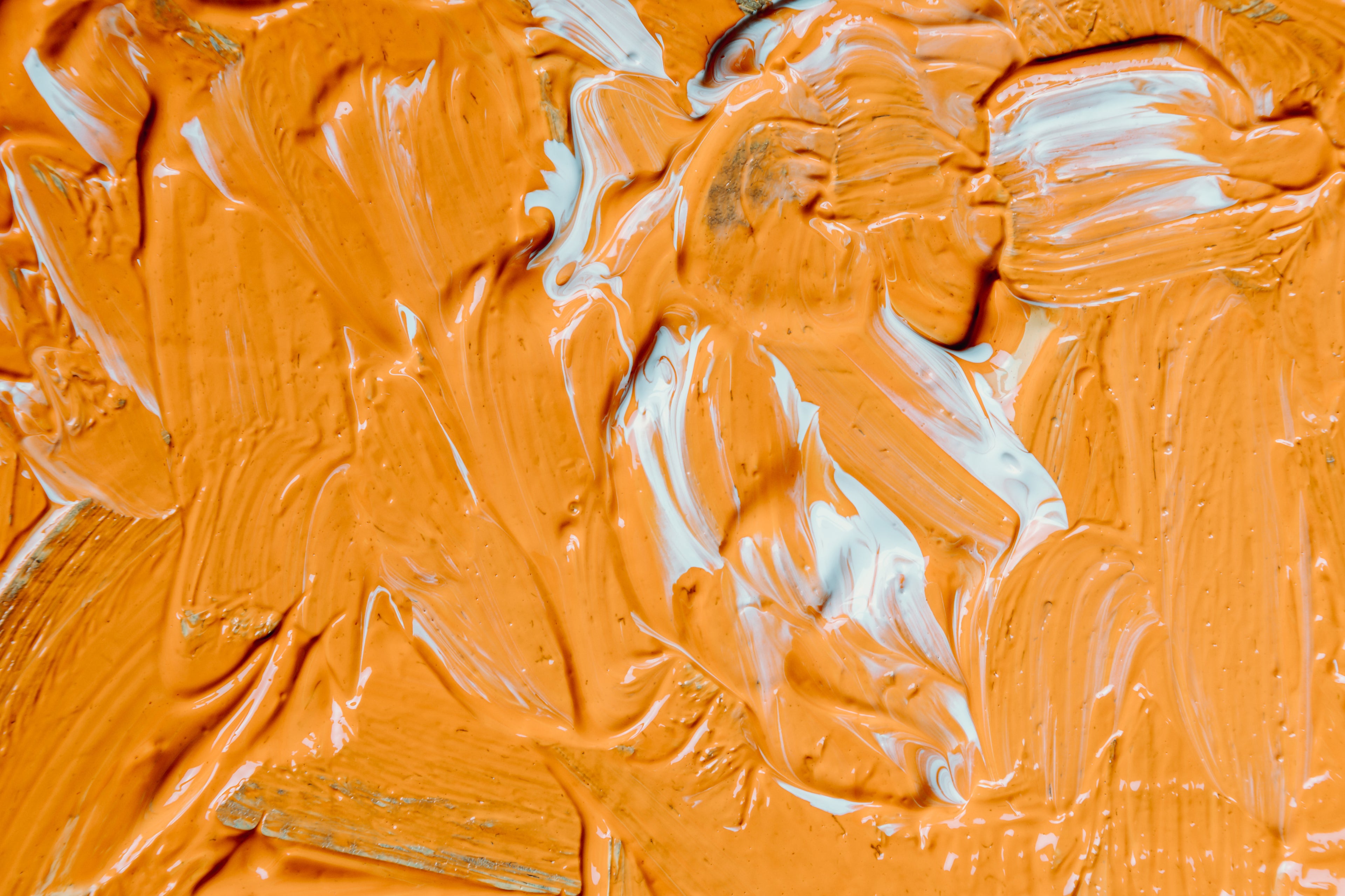 Orange and white paint spread across a canvas